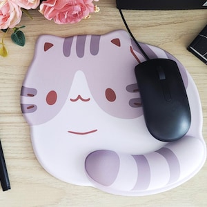 May include: A cat-shaped mousepad with a black mouse on top. The mousepad is light purple and white with a cat face design. A black stylus and a notebook are also visible.