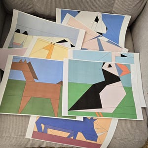 May include: A collection of geometric art prints featuring animal illustrations. The prints showcase a brown horse, a black and white puffin, and other abstract animal designs. Each print has a white border and is set against a blue or green background.