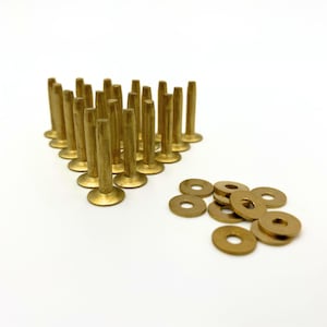 May include: A set of 25 gold-toned metal rivets and washers. The rivets are arranged in a triangular shape, and the washers are scattered around them.