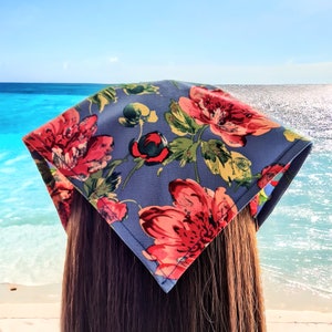 May include: A blue bandana with a floral print featuring red, pink, and white flowers. The bandana is tied around a person's head.