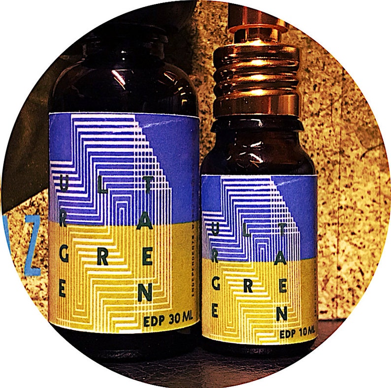 May include: Two glass bottles with brown caps and blue and yellow labels that say "Ultra Green" and have a geometric pattern. The larger bottle is 30 ml and the smaller bottle is 10 ml.