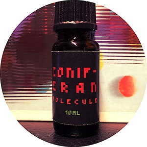 May include: A small, dark brown glass bottle with a black cap and label. The label has white text that reads "CONIF-ERAN MOLECULE 10ML" in a pixelated font. The text "CONIF-ERAN" is in red.