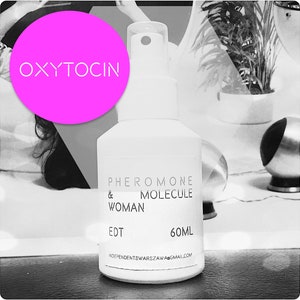 May include: A white bottle with a black label that reads "PHEROMONE & MOLECULE WOMAN EDT 60ML INDEPENDENTWARSAW@GMAIL.COM". The bottle has a black spray nozzle and is sitting on a white surface. A pink circle with the word "OXYTOCIN" in white text is in the background.