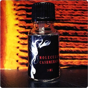 May include: A small, clear glass bottle with a black cap and a white label. The label says "MOLECULE CASHMERAN" and "10ML".