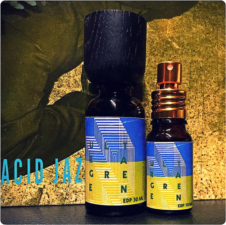 May include: Two glass bottles of perfume with a blue and yellow geometric design. The larger bottle is labeled "ULTRA GREEN EDP 30 ML" and the smaller bottle is labeled "ULTRA GREEN EDP 10 ML".