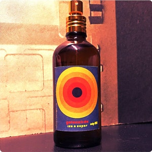 May include: A brown glass bottle with a gold spray nozzle and a label featuring a colourful concentric circle design. The label reads "golemkida 120 & super only 100".