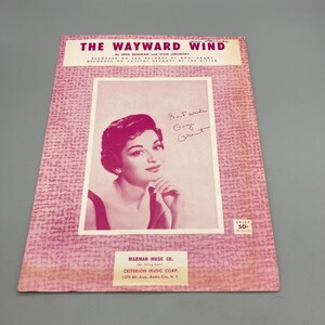 May include: A vintage sheet music cover for the song "The Wayward Wind" by Her Newman and Stan Lebowsky. The cover features a black and white photo of a woman with a signature that reads "Best wishes, Gogi Grant". The sheet music is published by Warman Music Co. and Criterion Music Corp.
