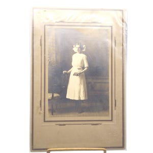 Fotografía vintage en blanco y negro de una joven encantadora con vestido blanco y lazo, con una Biblia, de Martin Studio.