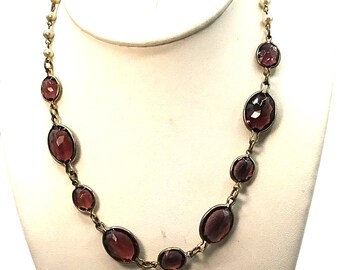 May include: A gold chain necklace with purple oval-shaped stones and small white pearl accents.