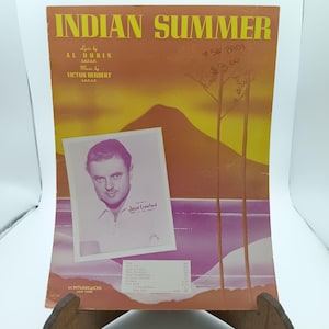 Puede incluir: Una portada de partitura vintage para la canción "Indian Summer" de Victor Herbert y Al Dubin. La portada presenta una escena de puesta de sol con una montaña y dos árboles. Una foto en blanco y negro de Jesse Crawford se encuentra en la esquina inferior izquierda. La partitura está publicada por M. Witmark & Sons, Nueva York.