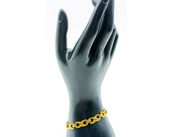 May include: A gold chain bracelet with a unique link design. The bracelet is displayed on a black mannequin hand.