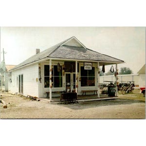 Cartão postal vintage dos antigos colonos e debulhadores do Centro-Oeste de Mt. Pleasant, Iowa, com fachada de loja de artigos gerais