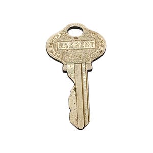 Può includere: Una chiave di metallo vintage con la parola "SARGENT" al centro. La chiave ha una parte superiore arrotondata con un foro e le parole "NEW HAVEN CONN. U.S.A." attorno al bordo. La chiave è di colore chiaro e invecchiato.