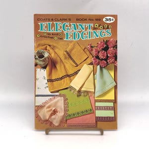 May include: Vintage book cover for Coats & Clark's Book No. 189, "Elegant Edgings." The cover features various crocheted and knitted edging designs in yellow, green, pink, and blue, with a floral arrangement and a small ceramic pitcher.