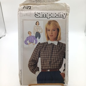 May include: Simplicity sewing pattern number 7172 for a blouse. The pattern is for sizes 30, 40, and 42. The pattern shows a woman wearing a plaid blouse with a white collar and a woman wearing a solid purple blouse with a white collar.