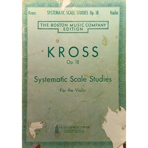Op de afbeelding: Een vintage muziekboek getiteld "Systematic Scale Studies" voor de viool van Kross, Op. 18. De omslag is verbleekt groen met de tekst in donkerder groen. Het boek is uitgegeven door The Boston Music Company.