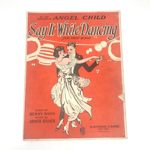 Puede incluir: Una portada de partitura vintage con fondo rojo que muestra a una pareja bailando. El título de la canción es "Say It While Dancing" y la música es de Abner Silver. La letra es de Benny Davis.