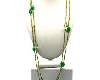 May include: A long, multi-strand necklace featuring thin, olive-green seed bead chains interspersed with larger, smooth, opaque emerald-green oval beads and translucent, faceted light-green crystal-like beads arranged in a repeating pattern.