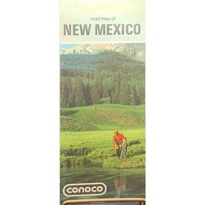 May include: A vintage road map of New Mexico, featuring a scenic illustration of a river, grassy field, and forest. The map includes the text "road map of NEW MEXICO" and the Conoco logo.