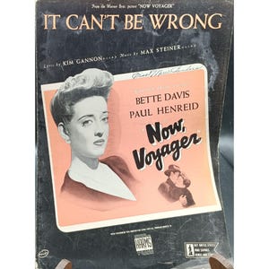 May include: Sheet music cover for "It Can't Be Wrong" from the film "Now, Voyager." The cover features a portrait of Bette Davis, the film's title, and the names of the lyricist and composer. The background is black with a peach-colored rectangle.
