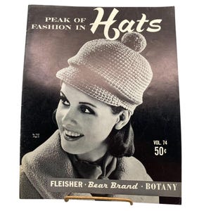 May include: A vintage black and white magazine cover titled Peak of Fashion in Hats Vol. 74. The cover features a person wearing a textured crocheted hat with a pom-pom on top. Text includes Fleisher, Bear Brand, Botany, and No. 7410 Page 2.