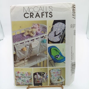 May include: A sewing pattern for baby items, including a crib organizer, a high chair tray, and a baby seat cover. The pattern is from McCall's Crafts and is size OSZ. The pattern includes instructions for making the items and is printed on a white background with black text.