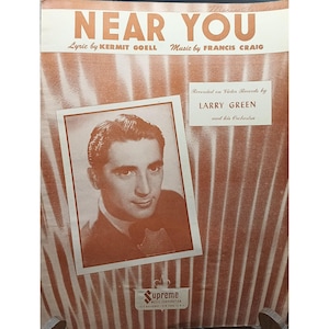 May include: Sheet music cover for "Near You" with a portrait of a man in a suit. The title is in large, orange letters, with the names of the lyricist and composer below. The text "Recorded on Victor Records by LARRY GREEN and his Orchestra" is also present.