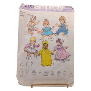 May include: Vintage Simplicity sewing pattern for small dolls, size 13"-14". The pattern features illustrations of six different doll outfits, including dresses, overalls, and a hooded jumpsuit. The pattern is printed on aged paper.
