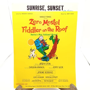 Może przedstawiać: Żółty plakat reklamujący musical "Skrzypek na dachu" z Zero Mostelem. Plakat przedstawia kreskówkową ilustrację mężczyzny grającego na skrzypcach na dachu. Tekst "Sunrise, Sunset" znajduje się na górze plakatu.
