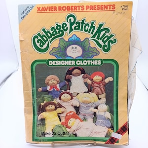 May include: A vintage Cabbage Patch Kids Designer Clothes pattern book. The cover features the Cabbage Patch Kids logo and illustrations of dolls in various outfits. The text reads "Xavier Roberts Presents" and "Make 25 Outfits".