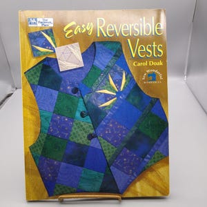 May include: A book titled "Easy Reversible Vests" by Carol Doak. The cover features a quilted vest in shades of blue and green, with gold accents. The book is part of the "Sew Wonderful Wearables" series.