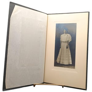 Vintage albumineportretfoto uit 1910 van vrouw in elegante jurk gemonteerd in zwarte kastkaart