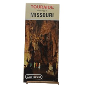 May include: A vintage Touraide road map of Missouri. The map features a detailed illustration of a cave interior with stalactites and stalagmites. The Conoco logo is visible at the bottom.
