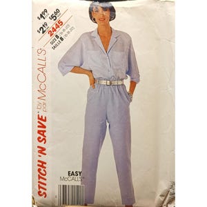Könnte beinhalten: Ein Vintage-Schnittmuster von McCall's für ein zweiteiliges Outfit. Das Muster zeigt ein hellblaues Hemd mit Kragen und Taschen sowie eine passende Hose. Das Model trägt einen Gürtel. Das Muster ist mit "Stitch 'N Save" und "Easy McCall's" gekennzeichnet.