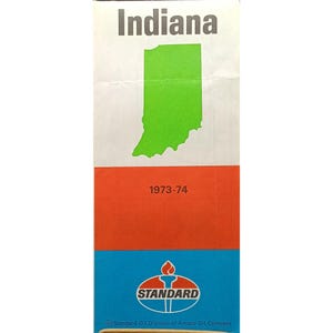 Puede incluir: Un anuncio vintage con la palabra "Indiana" en gris, un contorno verde del estado y los años "1973-74". La sección inferior muestra el logotipo de Standard Oil con una antorcha.