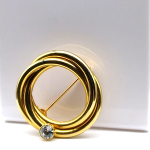 Broche vintage de anillos entrelazados pulidos en tono dorado con cristal transparente, elegante broche para solapa o bufanda.
