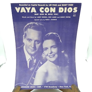 May include: Sheet music cover for "Vaya Con Dios" by Les Paul and Mary Ford. The cover features a black and white photo of a man and woman. The title is in large white letters on a blue background.