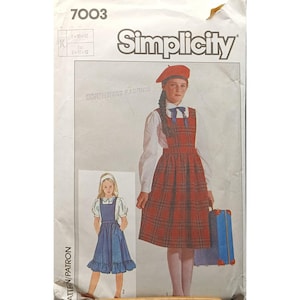 Puede incluir: Patrón de costura Simplicity con un vestido de peto a cuadros y un vestido azul. El patrón incluye el texto "7003" y "Simplicity". La imagen muestra a una niña con el vestido de peto a cuadros y otra niña con un vestido azul.