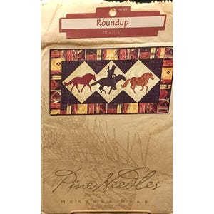 May include: A fabric panel labeled "Roundup" featuring a cowboy on horseback with two other horses. The panel is 39" x 21 1/2" and has a western theme with a brown, red, and gold color scheme.