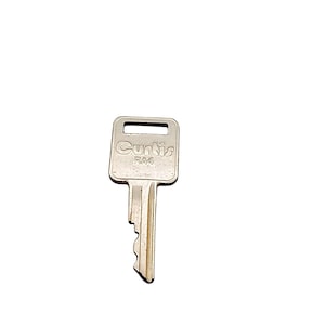 May include: A silver Curtis RA4 key with a rectangular head and a grooved blade. The brand name "Curtis" and "RA4" are printed on the key head. The key is designed for a lock.
