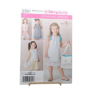 May include: A Simplicity 2391 sewing pattern envelope for pillowcase fashions in size A 3,4,5,6,7,8. The front displays illustrations of children wearing various sleeveless dresses and tops with matching bags, featuring floral embroidery and blue ribbon ties.
