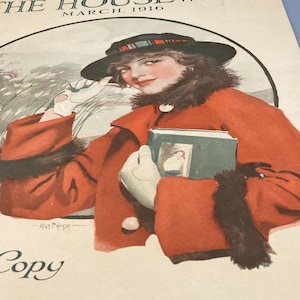 Może przedstawiać: Okładka vintage'owego magazynu przedstawiająca kobietę w czerwonym płaszczu i czarnym kapeluszu trzymającą książkę. Magazyn nosi tytuł "The Housewife", a data to marzec 1916.