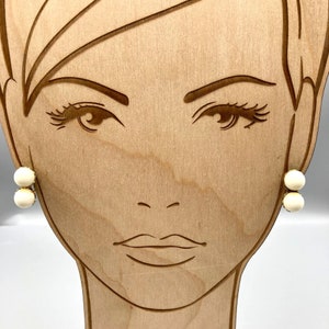 May include: A pair of gold stud earrings with two white pearl-like stones on each earring.