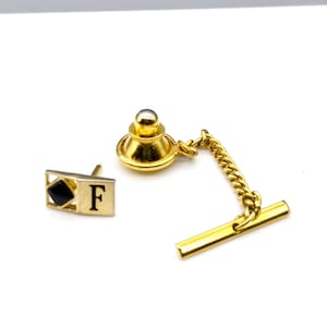 Può includere: Set di fermacravatta dorato. Il set include una spilla da cravatta con catena e barra, e un design rettangolare con la lettera "F" e un quadrato nero.