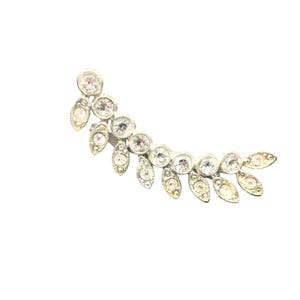 May include: A silver-toned ear cuff featuring a curved design with alternating round and oval-shaped clear crystals. The ear cuff has a delicate, elegant appearance, suitable for special occasions.