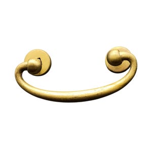 May include: A gold-toned metal drawer pull with rounded ends. The pull is shaped like a half-circle.