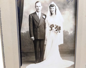 Vintage bruiloft kabinet kaart, speciale dag zwart-wit foto, Dapper bruidegom w blozende bruid in franje en bloemen, periode portret