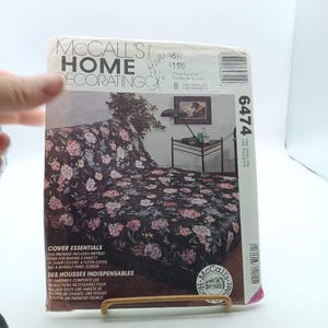 May include: McCall's Home Decorating pattern number 6474 for making a variety of chair covers, a futon cover, and a shirred panel screen. The pattern cover shows a floral patterned futon with a black background.