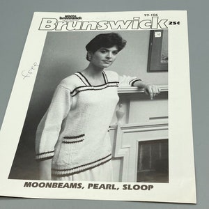May include: A black and white photo of a woman wearing a white knitted sweater with black and white stripes. The sweater has a pocket on the front. The photo is from a knitting pattern magazine called "Home Brunswick" and the pattern number is 99-106.