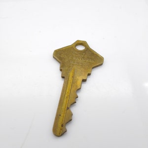 以下が含まれることがあります： 上部に「COLE NATIONAL U.S.A.」と刻まれた、ギザギザの縁のある金色の鍵です。